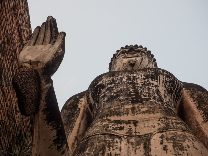 Low angle view of buddha statue at sukhothai historical park, thailand