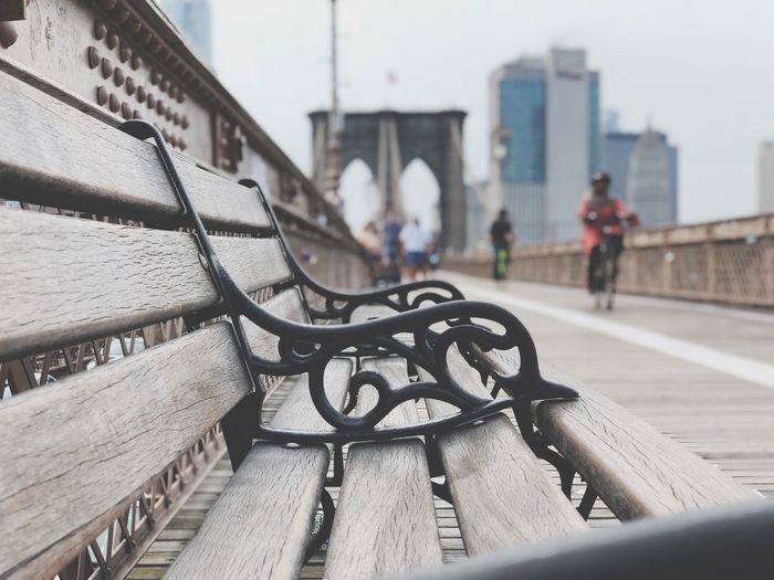 Empty bench against brooklyn bridge in city