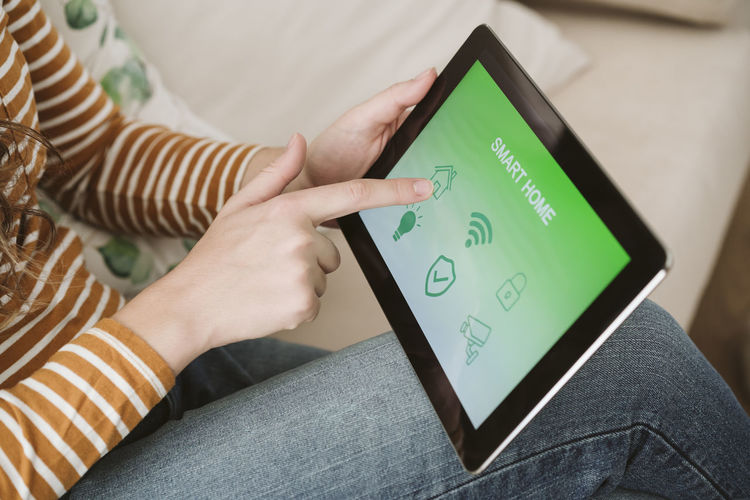Close-up of woman using digital tablet with smart home app