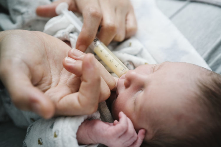 Woman feeding newborn baby boy with injection in hospital