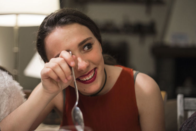 Smiling woman with spoon looking away