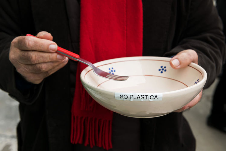 No plastic plate, the hands of an elderly activist hold a plate with the inscription no plastic