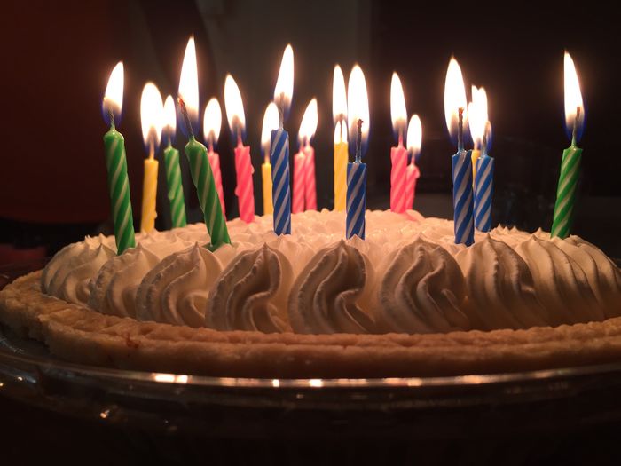 Close-up of lit candles on birthday pie in darkroom