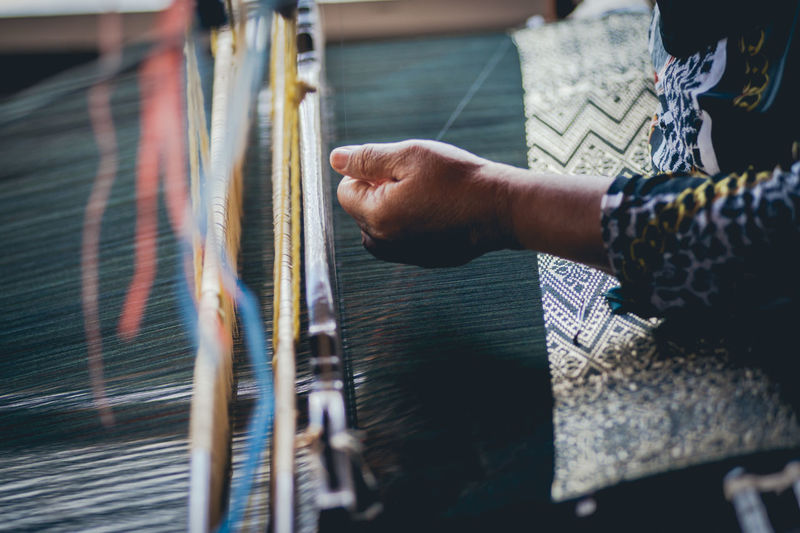 Midsection of woman weaving textile at loom