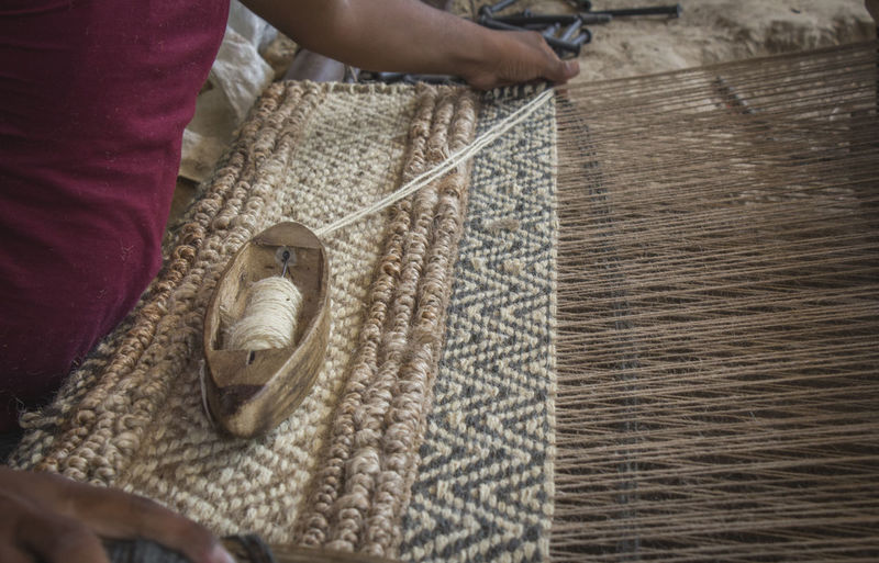 Midsection of man weaving textile