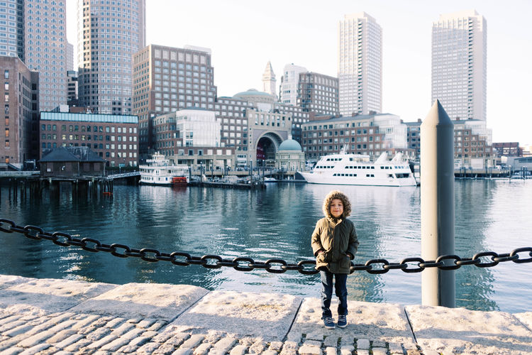 Photo of a boy at the boston harbor during a sunset.