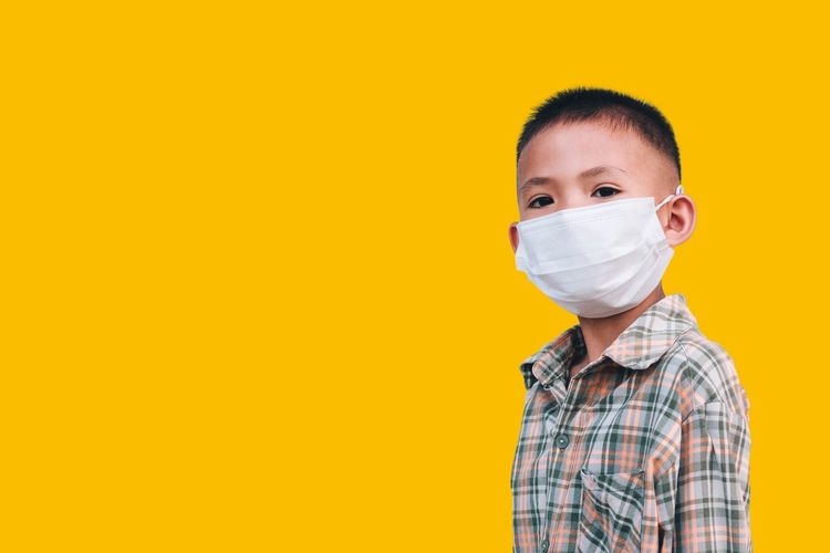 Portrait of boy wearing mask against yellow background