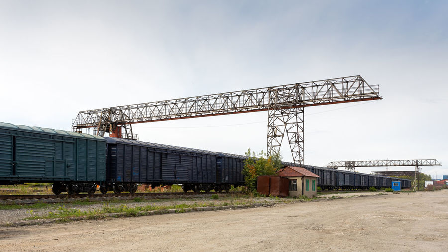Large metal gantry cranes at a on the railway platform, standing on freight wagons for storing goods