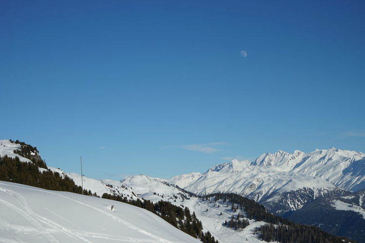 Scenic view of snow covered mountains against clear blue sky