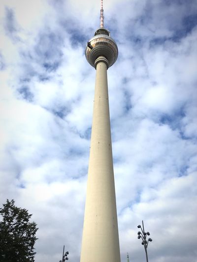 Low angle view of communications tower against cloudy sky