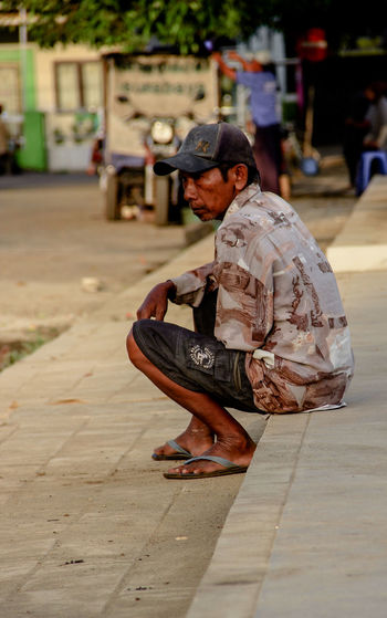 Side view of man sitting on street
