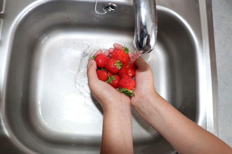 Cropped image of hand holding strawberry at home