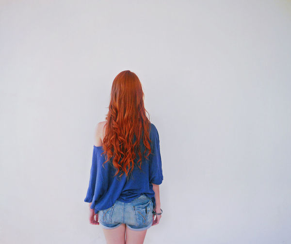 Rear view of young woman standing against white background