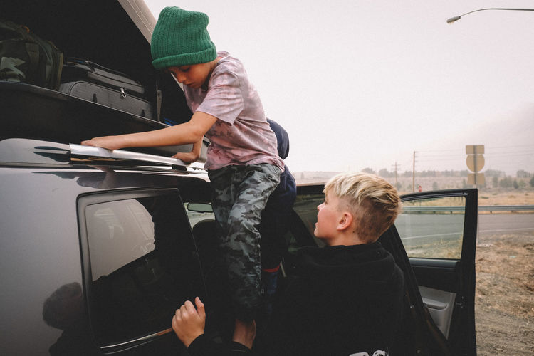 Brothers checking on a luggage rack while on a road trip.