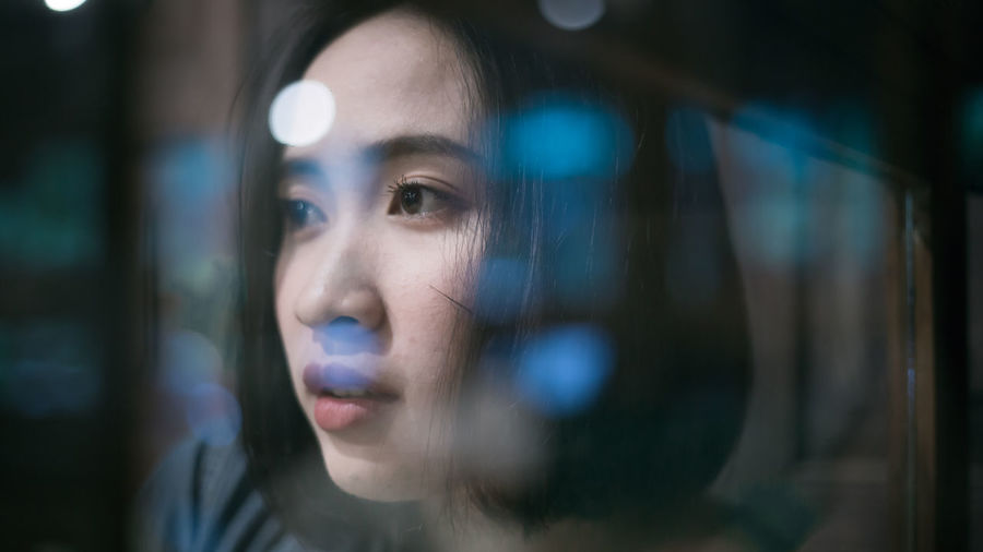 CLOSE-UP PORTRAIT OF YOUNG MAN LOOKING THROUGH GLASS