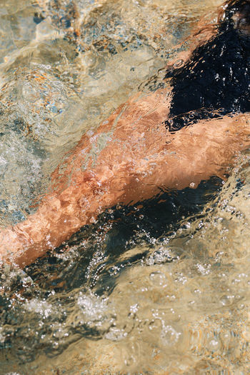 Low section of man swimming in water