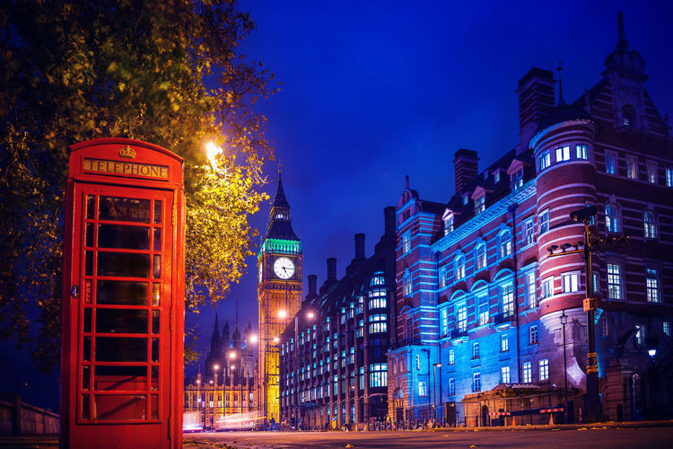 Telephone booth with illuminated city buildings in background