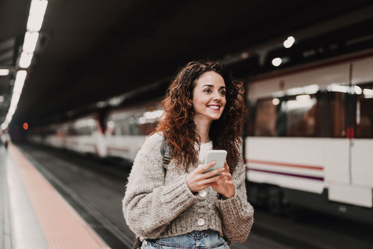 Portrait of smiling woman standing at railroad station