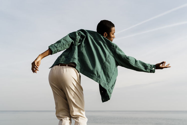 SIDE VIEW OF TEENAGE BOY AGAINST SEA