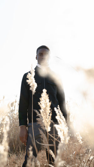 MAN STANDING ON FIELD AGAINST SKY