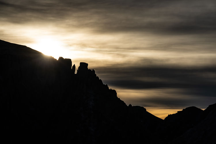Silhouette rocks against sky during sunset