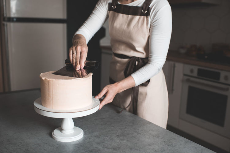 Woman making creamy birthday cake in kitchen closeup. holiday time. selective focus.