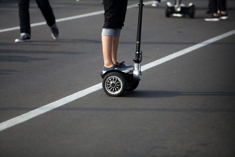 Low section of woman standing on segway over road
