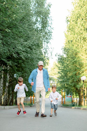 Family walking in park. dad and sons are running. happy dad with children