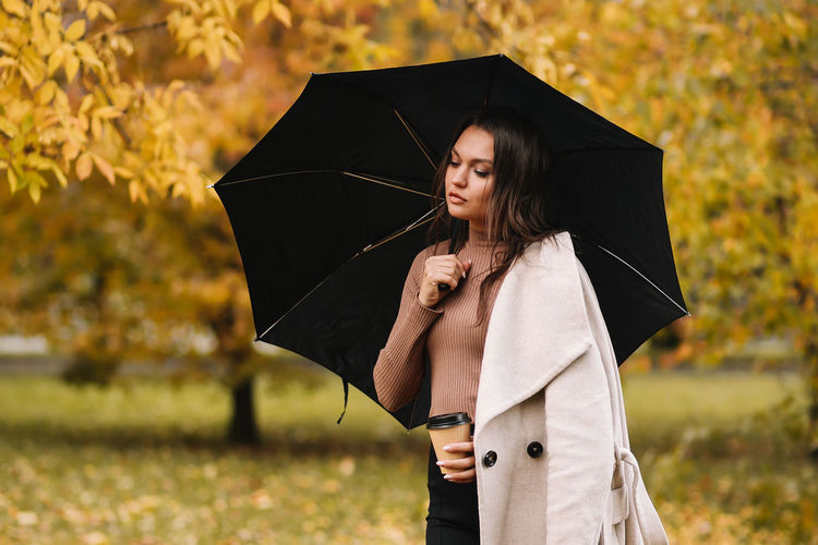 Woman standing with umbrella in rain during autumn