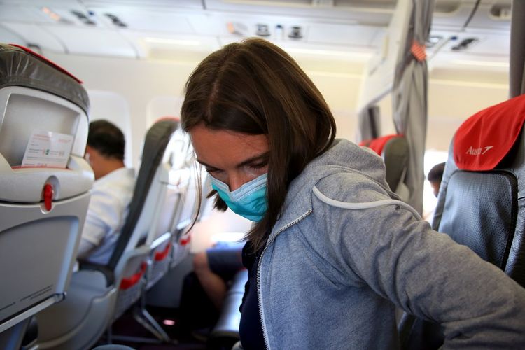 Close-up of woman wearing flu mask sitting in airplane