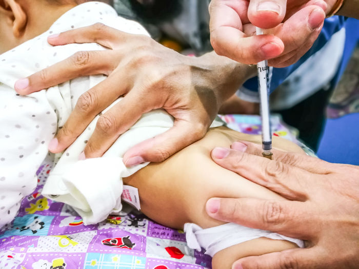 Cropped hands of doctor injecting baby in hospital