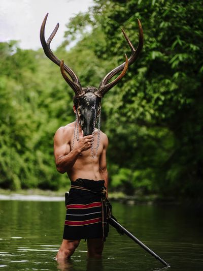 Full length of shirtless man standing in lake