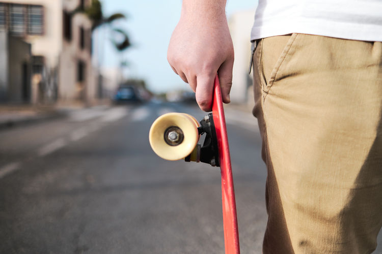 Unrecognizable young man with red skateboard in the street