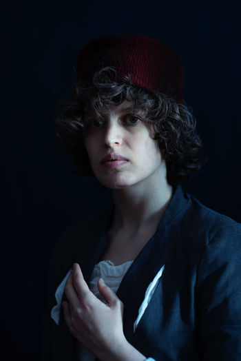 Close-up portrait of girl wearing hat against black background