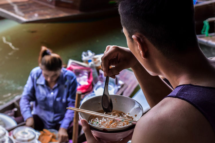 Man eating food in bowl against floating market