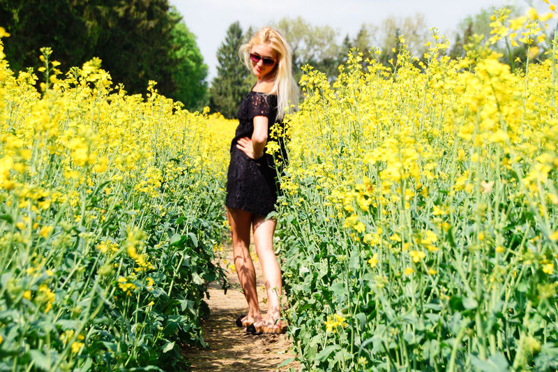 Young woman standing amidst yellow flowers on oilseed rape field