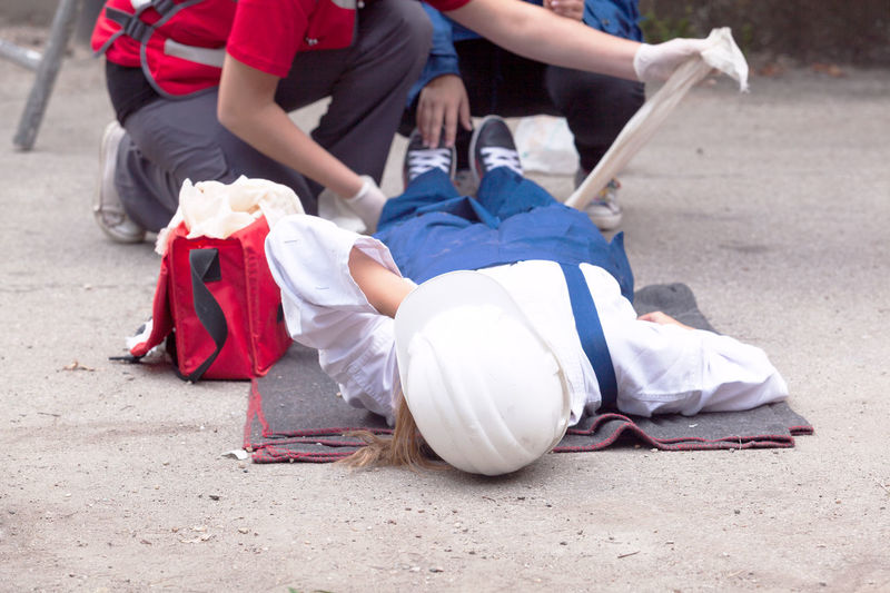 Paramedics performing cpr on women lying on street