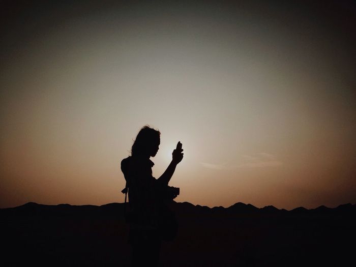Silhouette of young woman texting