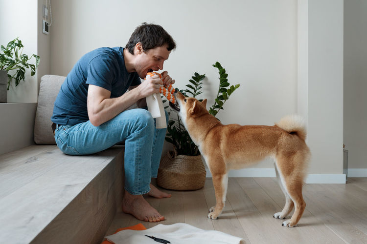 Funny adult man playing with a homemade dog toy with his favorite furry dog friend