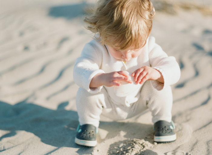 Cute baby girl sitting on sand at beach