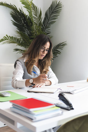 Young lawyer making notes sitting at desk in office