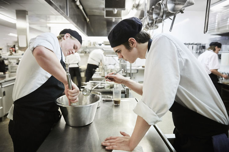 Side view of male chef students making food in commercial kitchen
