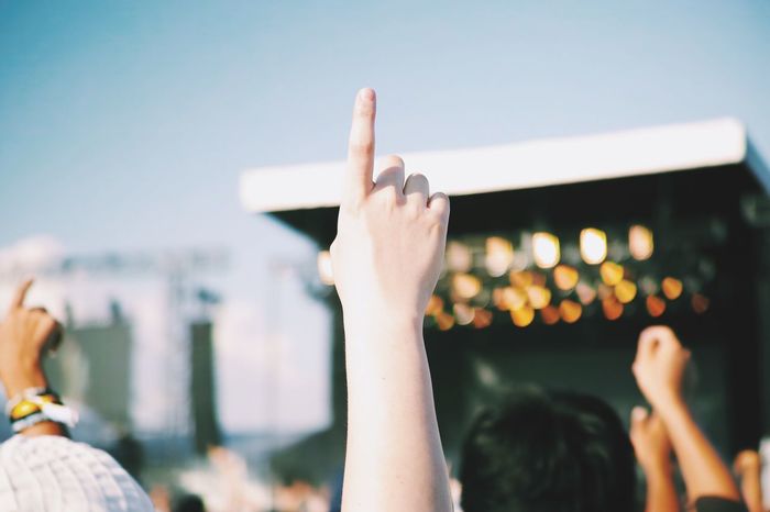 Cropped image of people pointing towards sky in music concert