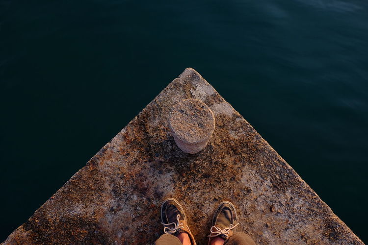 Low section of man standing on rusty pier over river
