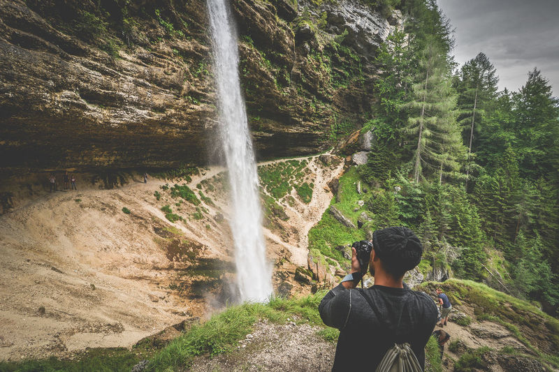 Man photographing of waterfall in forest