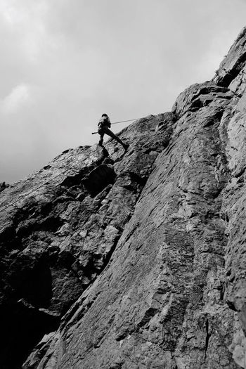 Low angle view of person on rocky mountain against sky