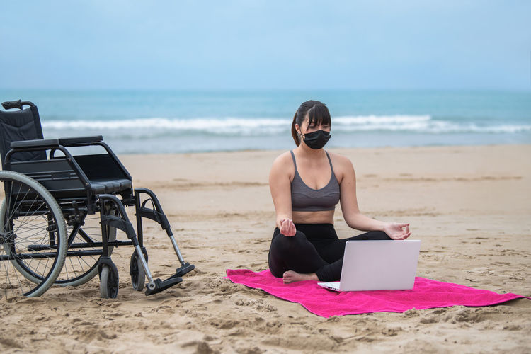 Disabled woman practicing yoga at beach