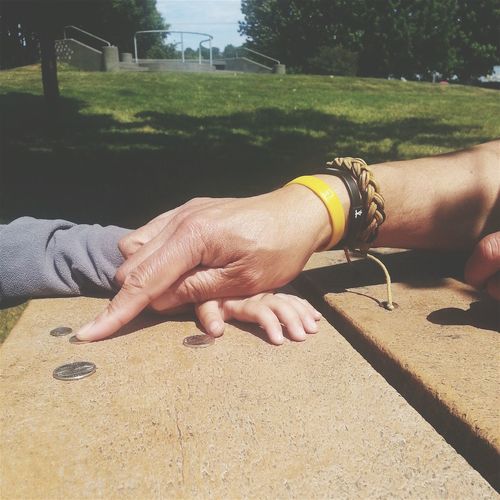 Cropped hands of father and son with coins on stone table in park