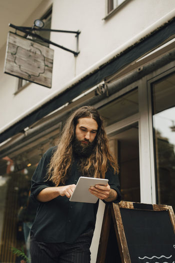 Businessman using digital tablet outside retail store