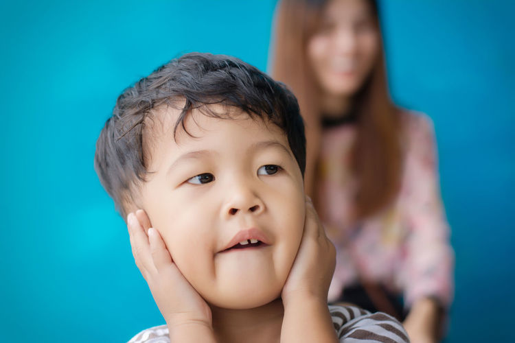 Cute boy covering ears with hands while looking away